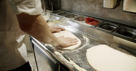 Cropped view on professional man chef hands cooking italian pizza and prepare dough base at restaurant kitchen. Process of making pizza. Food concept.