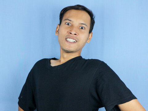 Angry young Asian man expression with pointing gesture and bulging eyes. Mental health concept
