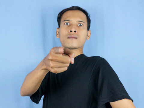 Angry young Asian man expression with pointing gesture and bulging eyes. Mental health concept
