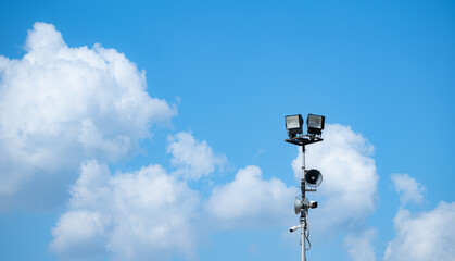 Blue sky background with white clouds and broadcasting speakers with the spotlight