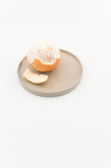 immagine con primo piano di frutti di arancia sbucciata, su piccolo piatto superficie bianca