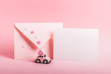 Bishkek, Kyrgyzstan - December 4, 2023: Small pink car model with a heart-shaped marshmallow and an envelope decorated with buttons on a pink background. Concept for Valentine's Day. - obrazy, fototapety, plakaty