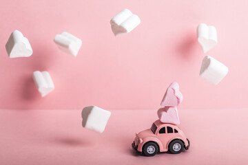 Bishkek, Kyrgyzstan - December 4, 2023: Small pink car model with two heart-shaped marshmallows in...