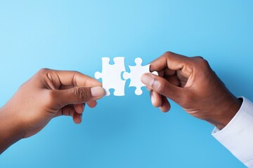 close up image of two businesspeople connecting jigsaw puzzle pieces on blue background. business solutions and success concept.
