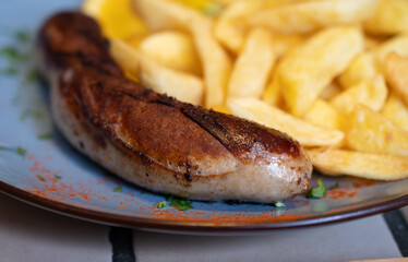 Fried fries potatoes with grilled meat German sausage served in old restaurant in Germany