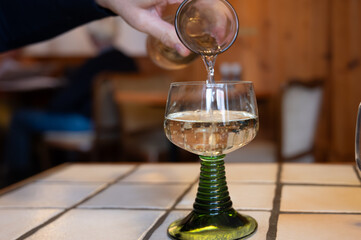 White quality riesling wine served in green swirl wine glass in old German restaurant in Monschau village, Germany - obrazy, fototapety, plakaty