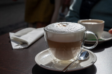 Drinking tasty fresh brewed Italian caffe latte coffee with whipped milk in outdoor cafe