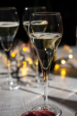 New year party, small bubbles of brut champagne cava or prosecco wine in tulip glasses with garland  lights on background