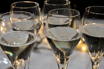 New year party, small bubbles of brut champagne cava or prosecco wine in tulip glasses with garland  lights on background