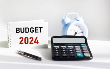 BUDGET 2024 written on a notepad and white background and with a calculator clock