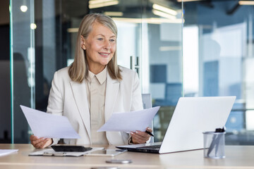 Senior female accountant financier at workplace inside office paperwork, businesswoman satisfied...