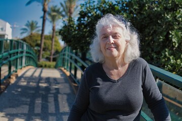 Portrait of a smiling gray-haired lady on a pedestrian bridge.Copy space.