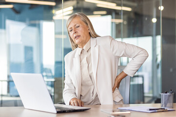 Long sitting work inside office, overworked tired gray haired senior woman has severe back pain,...