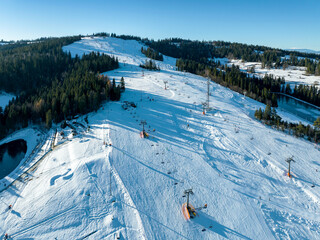 Ski slope, chairlifts, skiers and snowboarders in Bialka Tatrzanska ski resort in Poland on...