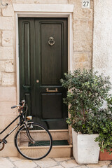 Bike parked near green door of old stone house in Polignano a Mare old town