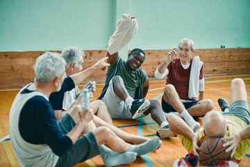 Senior friends share a joyful moment during a break in their indoor basketball game