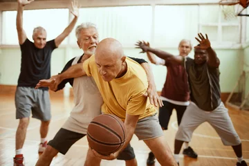 Fotobehang Group of active senior men playing basketball indoor © Geber86