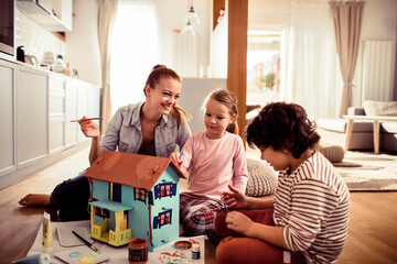 Young family painting a doll house at home