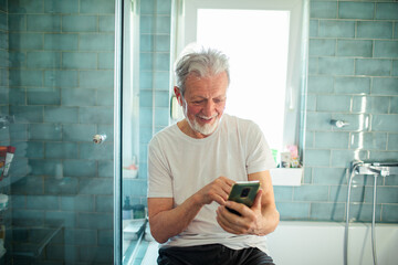 Smiling senior man using smartphone in the bathroom