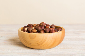 Wooden bowl full of hazelnuts on table background. Healthy eating concept. Super foods