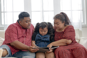 Happy Asian family using tablet. Asian Chubby father mother and kid playing game watching movies. Relaxing at home for lifestyle concept.