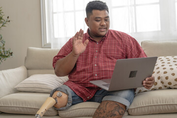 Asia man working with tablet in a sofa in the living room. male with mechanic steel leg sitting and...