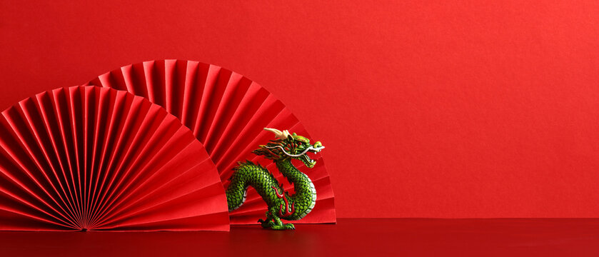 Lunar New Year 2024 background. Chinese dragon with red paper fans on red background.