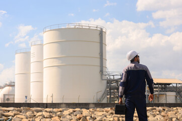 Engineers wearing safety vests inspect and repair systems in the refinery area.