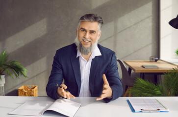 Smiling businessman entrepreneur in suit talking to camera. Bearded middle aged ceo coach speaker, trainer in suit recording online business training, making conference video call, webcam view