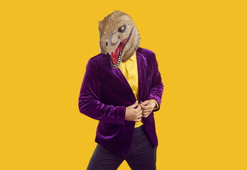 Man in dinosaur costume posing in fashion studio. Portrait of funny male model in purple velvet...