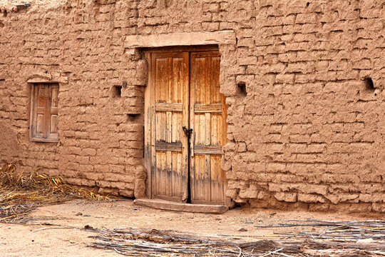 Uninhabited and old adobe house with wooden door in a rural area.