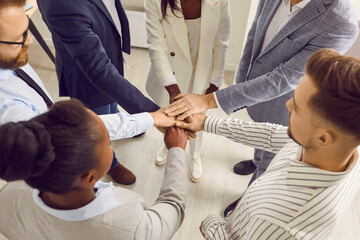 Close up top view photo of diverse business people putting their arms together. Stack of hands of a...