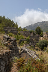 Abandoned Village of Kayakoy are many deserted stone houses with empty windows, without roofs, damaged stone walls. Dead city looks like ancient ruins