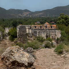 Fototapeta premium Abandoned Village of Kayakoy: many deserted stone houses, dead city looks like ancient ruins. Yukari Kilise is an old Greek damaged church.