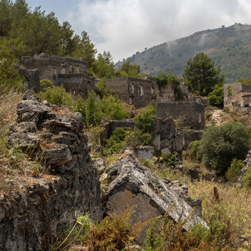 Abandoned Village of Kayakoy are many deserted stone houses with empty windows, without roofs, damaged stone walls. Dead city looks like ancient ruins