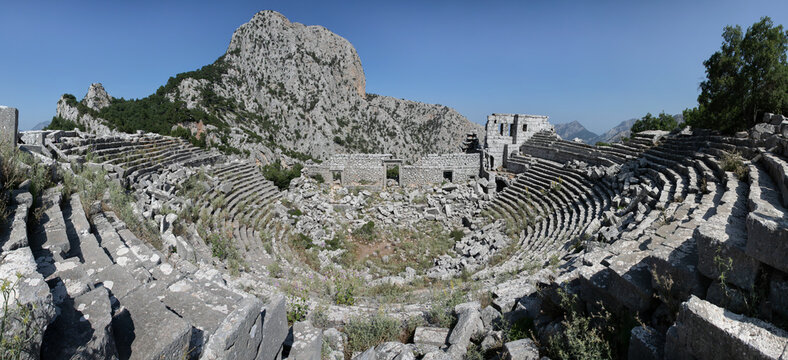 Glued wide panorama of amphitheatre ancient ruins. Remains of ancient Lycia civilization, Termessos dead antique city in Turkey. Mountain landscape.