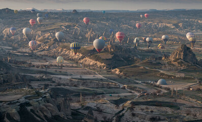 many hot air balloons during sunrise over the volcanic landscape of Cappadocia, Turkey