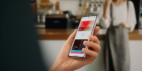 CU Man is paying with a card linked to his smartphone at the cafe