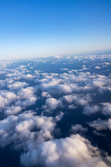 Top view of white fluffy clouds and clear sky above them