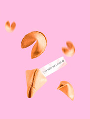 Fortune cookies with text you will be loved fly on pink background. Minimal art Valentine's day...
