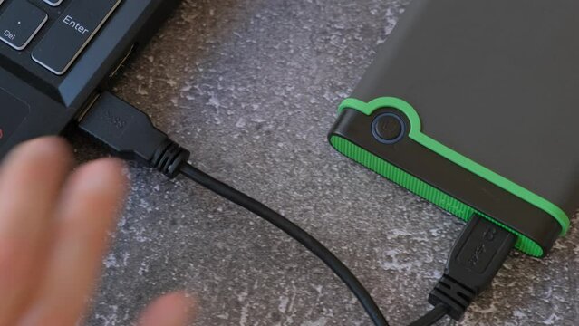 Portable hard drive connected to laptop to transfer data or documents, close-up