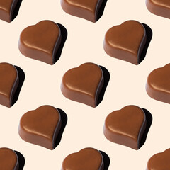 Seamless pattern of heart-shaped chocolates with a shadow on a beige background. Favorite food background. A symbol of love