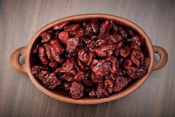 Delicious dried cranberry in a handmade ceramic tank on a brown table