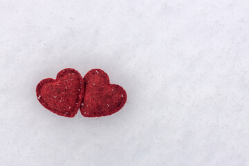 two red woolen hearts on a background of white snow, Valentine's card
