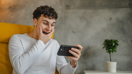 Fototapeta premium Portrait of teenage boy at home use smartphone to watch video podcast