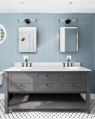 A blue wood panel bathroom with a grey cabinet, white marble countertop, and a black and white...