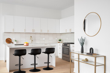 A kitchen detail with white cabinets, a picket tile backplash, white bar stools sitting at the...