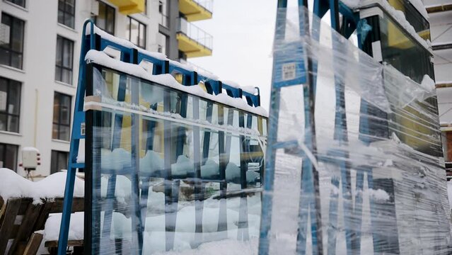 Work in progress on construction residential building. An uninstalled double-glazed window is packed and wrapped in film outdoor in winter
