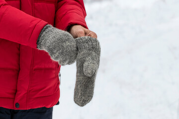 A man puts on knitted mittens on the street in winter.Warm clothes for winter walks.