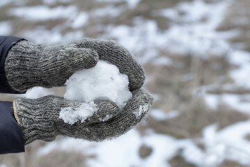 Woman in Winter gloves making snowball. Playing active games in winter. Hands in knitted mittens holding snowball. Wintertime leisure cold weather.
